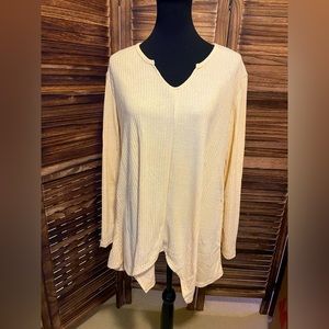 Cream colored long sleeve top. V-neck with uneven hemlines.